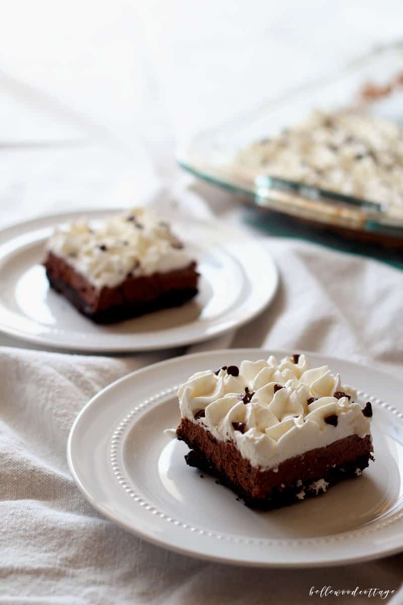 A slice of a layered French Silk Pie dessert topped with piped whipped cream and mini chocolate chips.