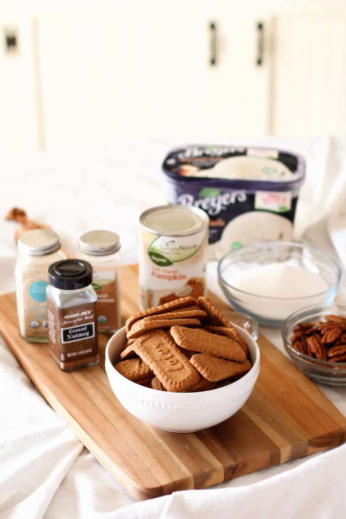 A bowl of ginger cookies surrounded by more ingredients including sugar, vanilla ice cream, and spices.