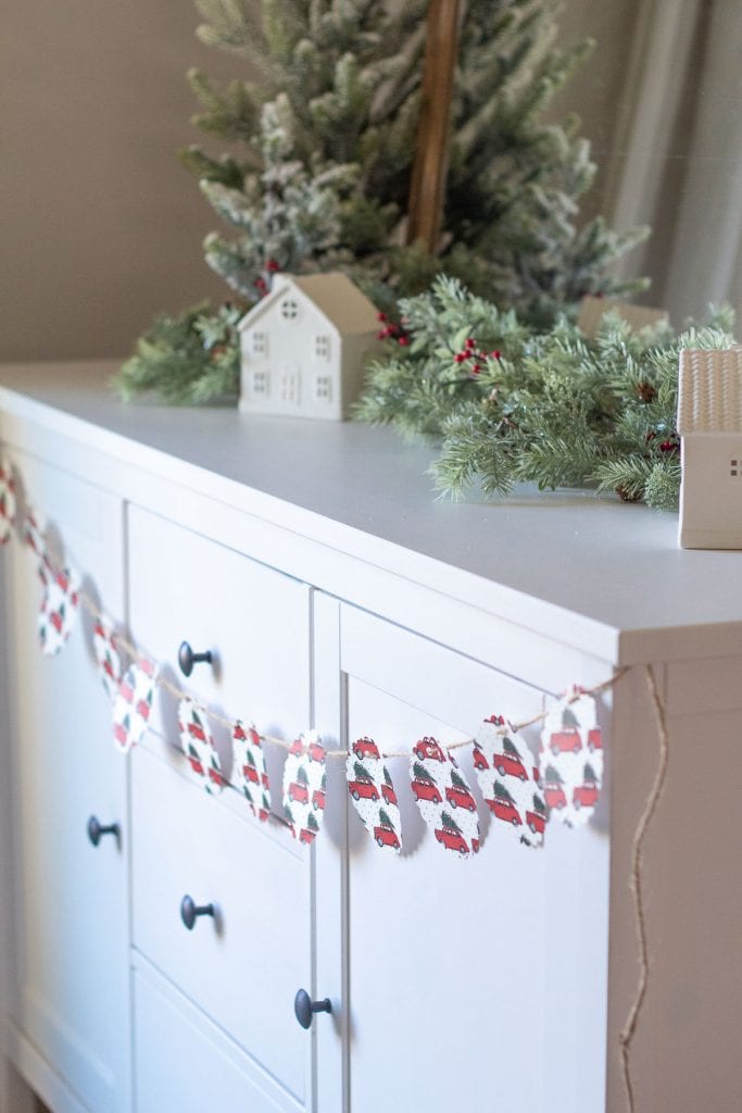 A Christmas Garland made from scrapbook paper hanging across a white sideboard.