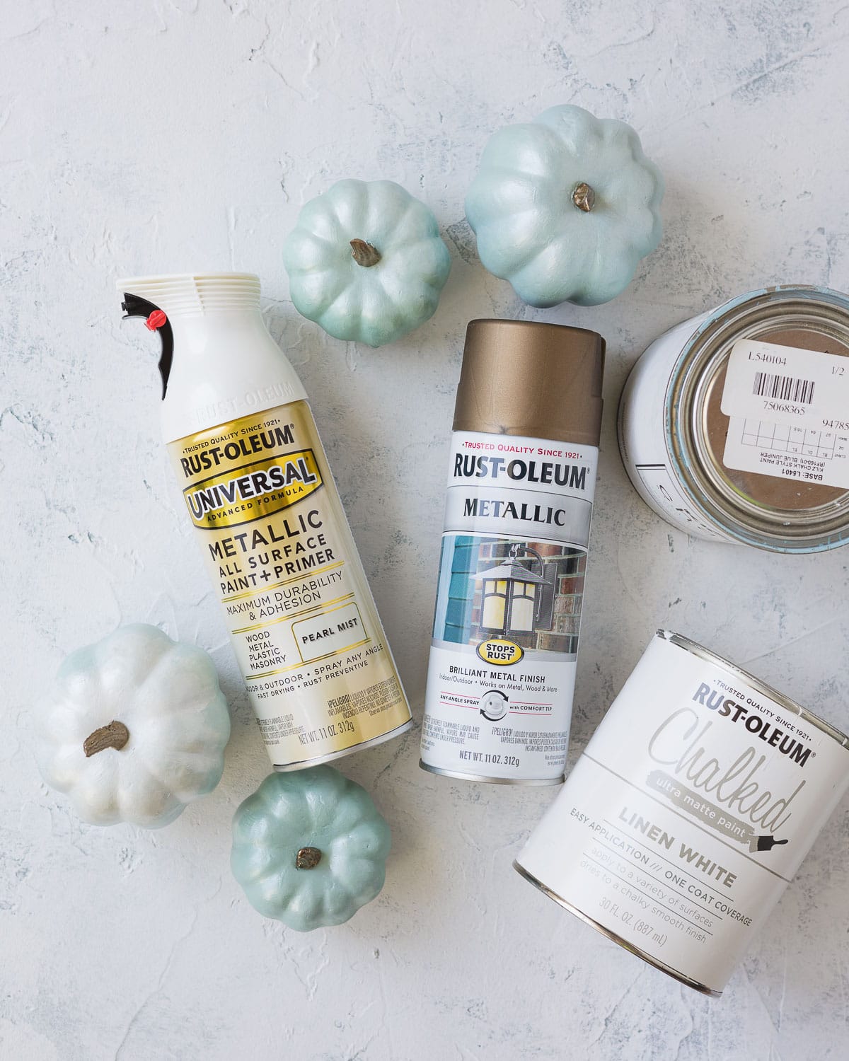 Spray paints, chalk paint, and DIY chalk painted pumpkins on a rustic surface.