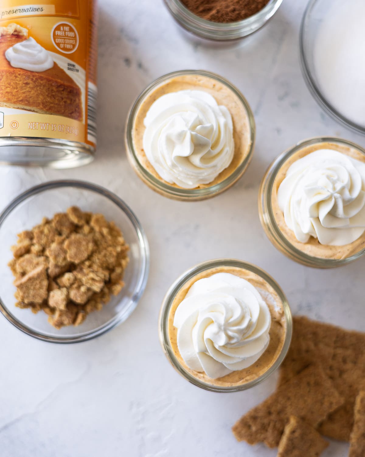 Mini mason jar pumpkin cheesecakes topped with rosettes of whipped cream.
