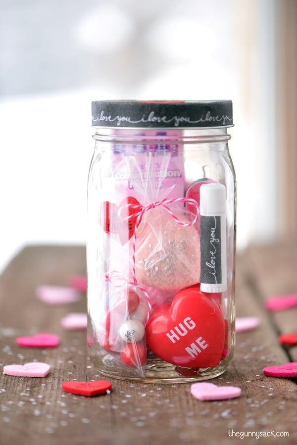 A mason jar filled with small Valentine's gifts.