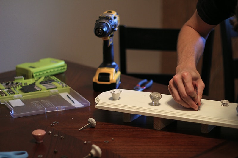 Attaching knobs to a DIY necklace organizer.