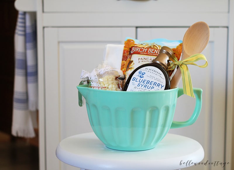 A green batter bowl filled with items to create a bridal shower gift basket.