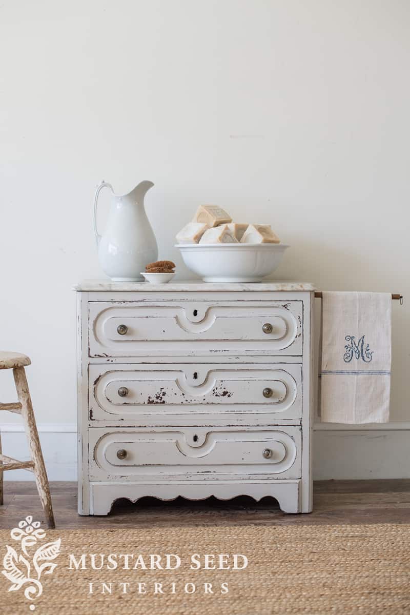 A white ironstone pitcher on an antique washstand.