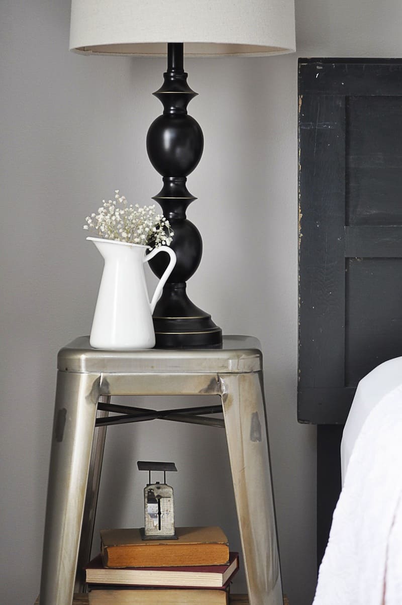 A nightstand display with a lamp and flowers.