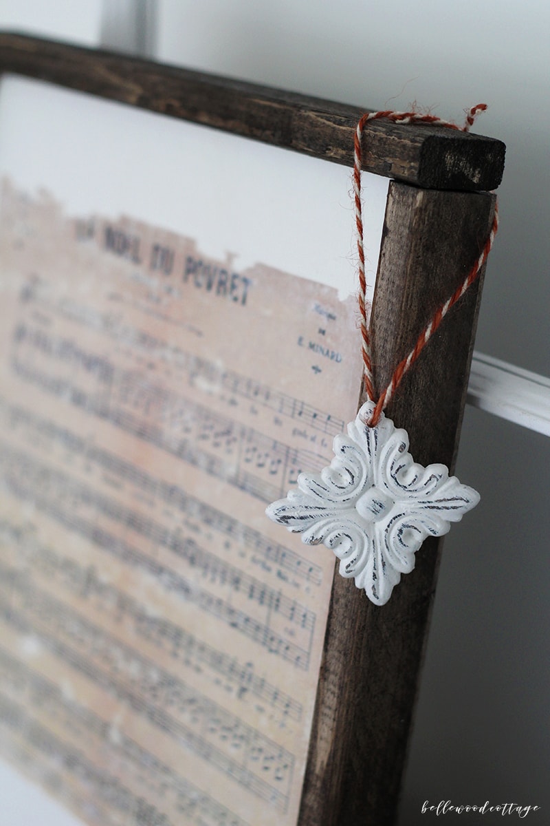 A DIY farmhouse Christmas ornament hanging off a Christmas print.