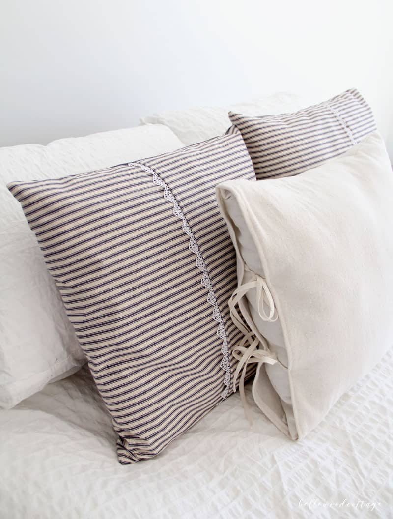 Ticking stripe pillows and drop cloth pillows arranged on a bed.