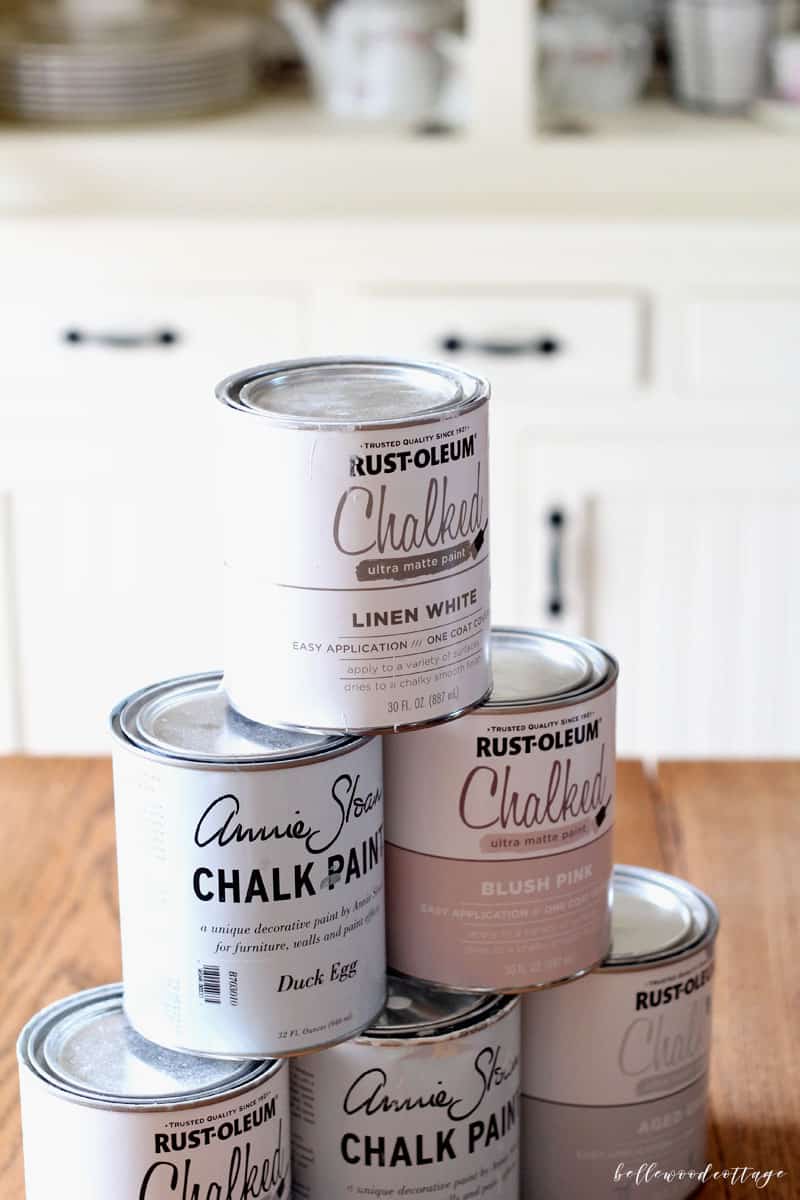 Cans of various brands of chalk paint on a table.