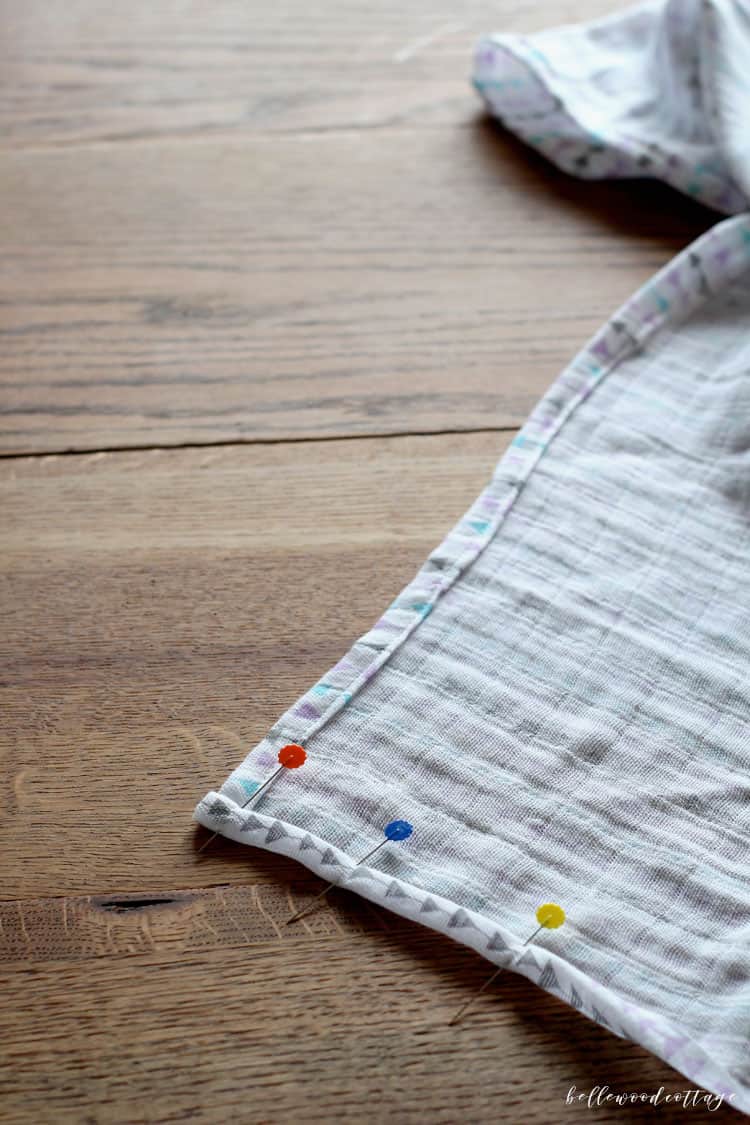 Pinning the hems of a baby swaddle blanket.