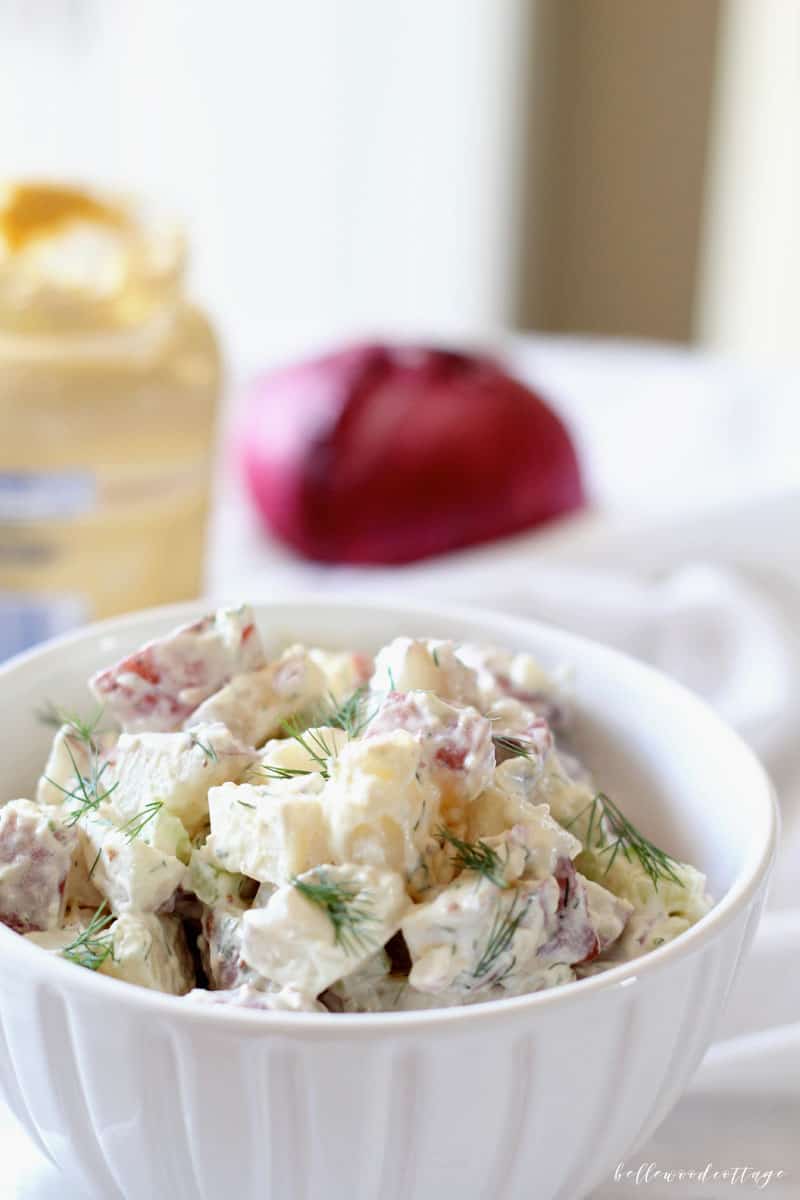 Bowl of potato salad garnished with fresh dill.