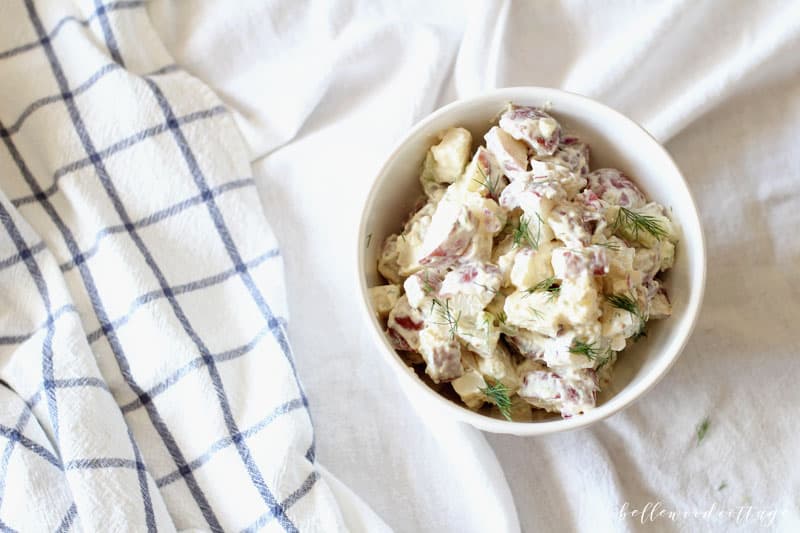 A blue and white towel and a bowl of potato salad.