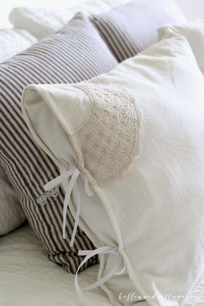 Learn how to make DIY drop cloth pillows using bleached drop cloths, antique lace, and a fun tecnhique that will make one pillow cover look like two!