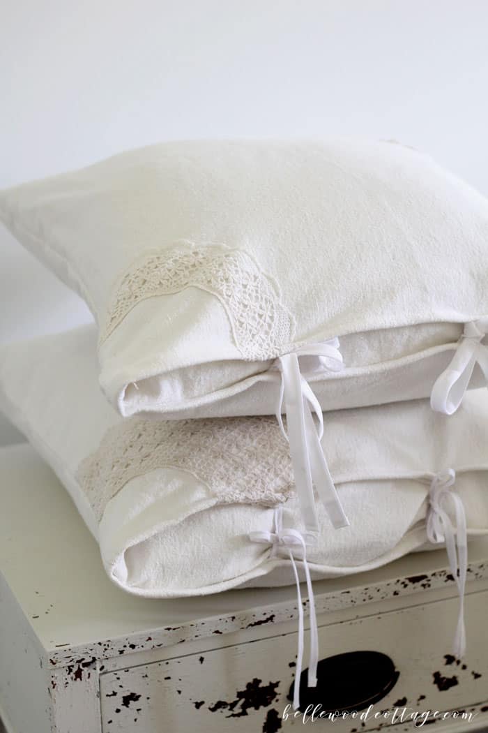 Learn how to make DIY drop cloth pillows using bleached drop cloths, antique lace, and a fun tecnhique that will make one pillow cover look like two!