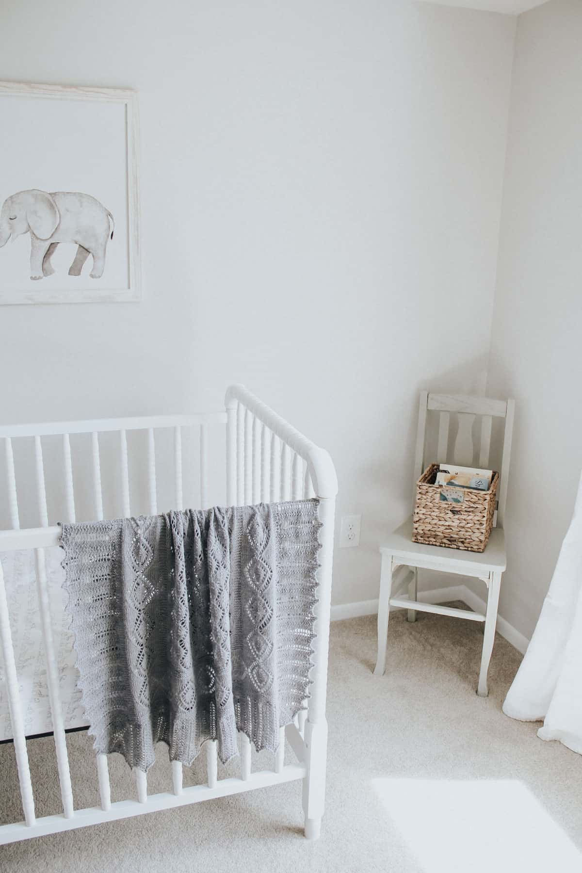 Hand knit blanket on a white Jenny Lind crib.