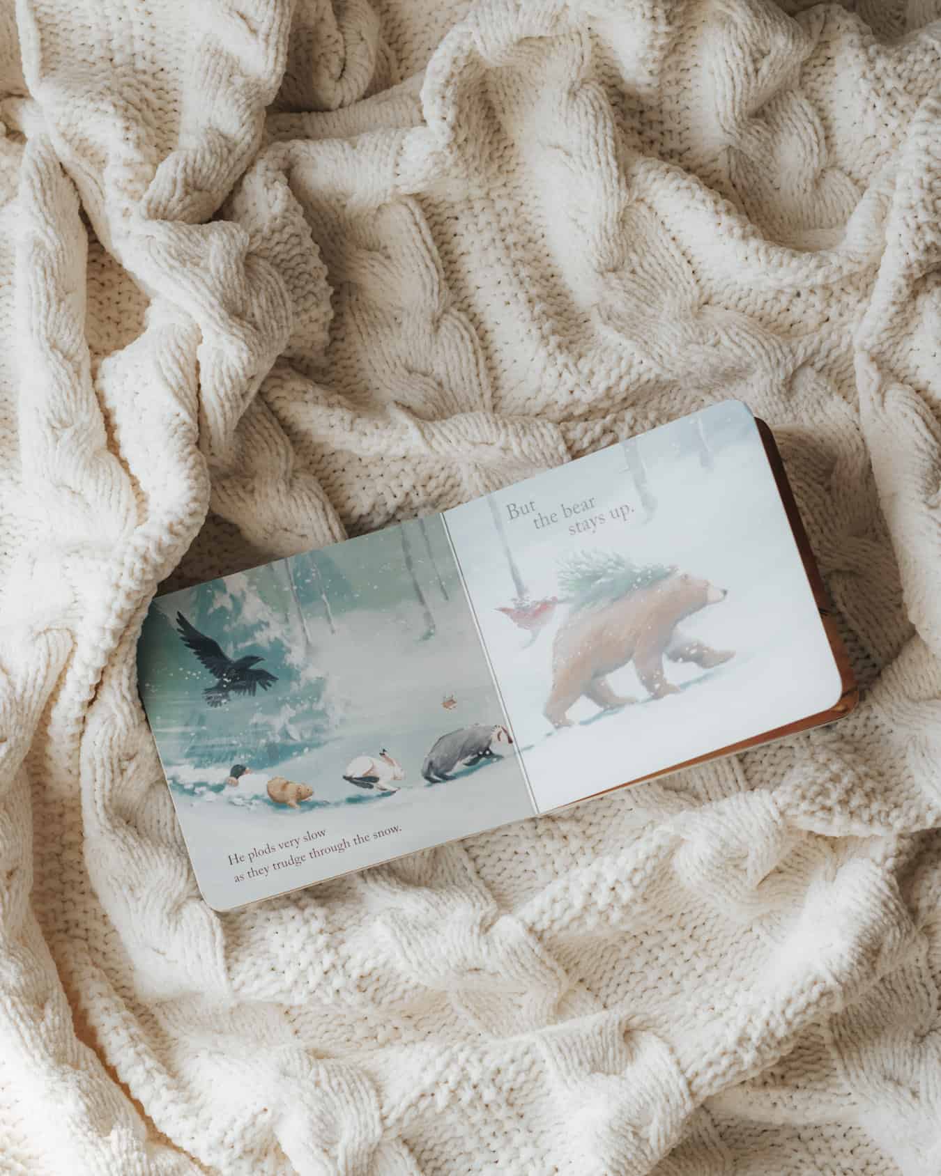 A book, Bear Stays Up for Christmas, on a cream-colored blanket.