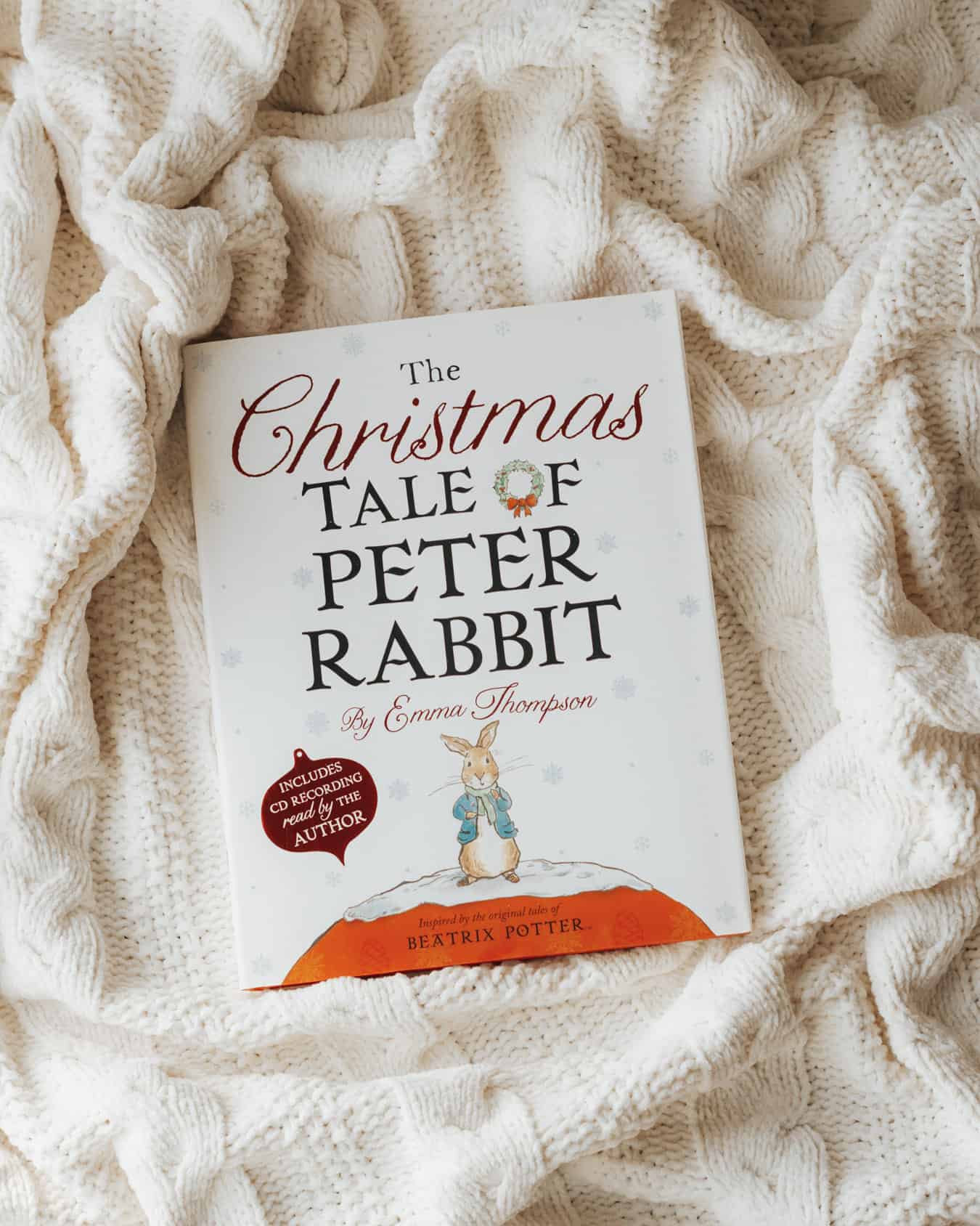 A book, The Christmas Tale of Peter Rabbit, on a cabled blanket.