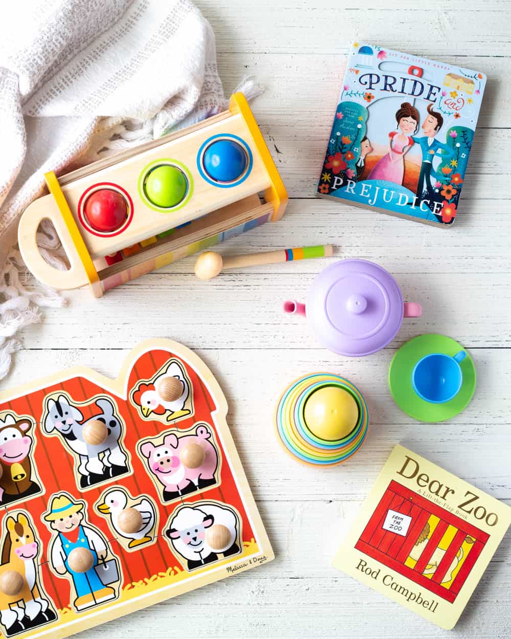 Educational toys under $25 for one-year-olds including, toddler puzzles, stackers, books, and a xylophone on a wooden surface.