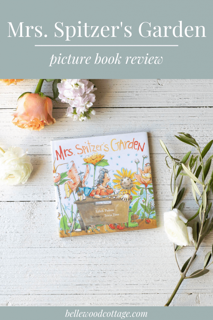 Mrs. Spitzer’s Garden picture book on a wooden surface surrounded by flowers.