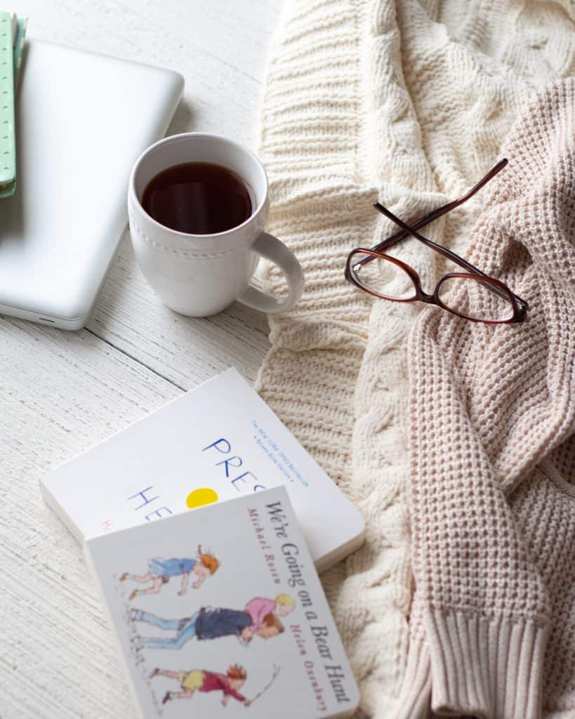 Board books, glasses, and tea on a wooden surface.