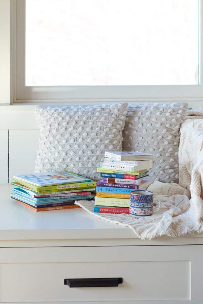 Stacks of kids' books on a window seat represent how to read aloud every day with kids and babies.