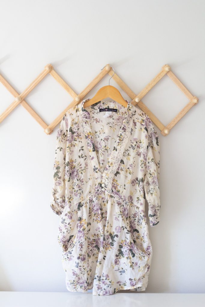 A women's blouse on a wooden hanger.