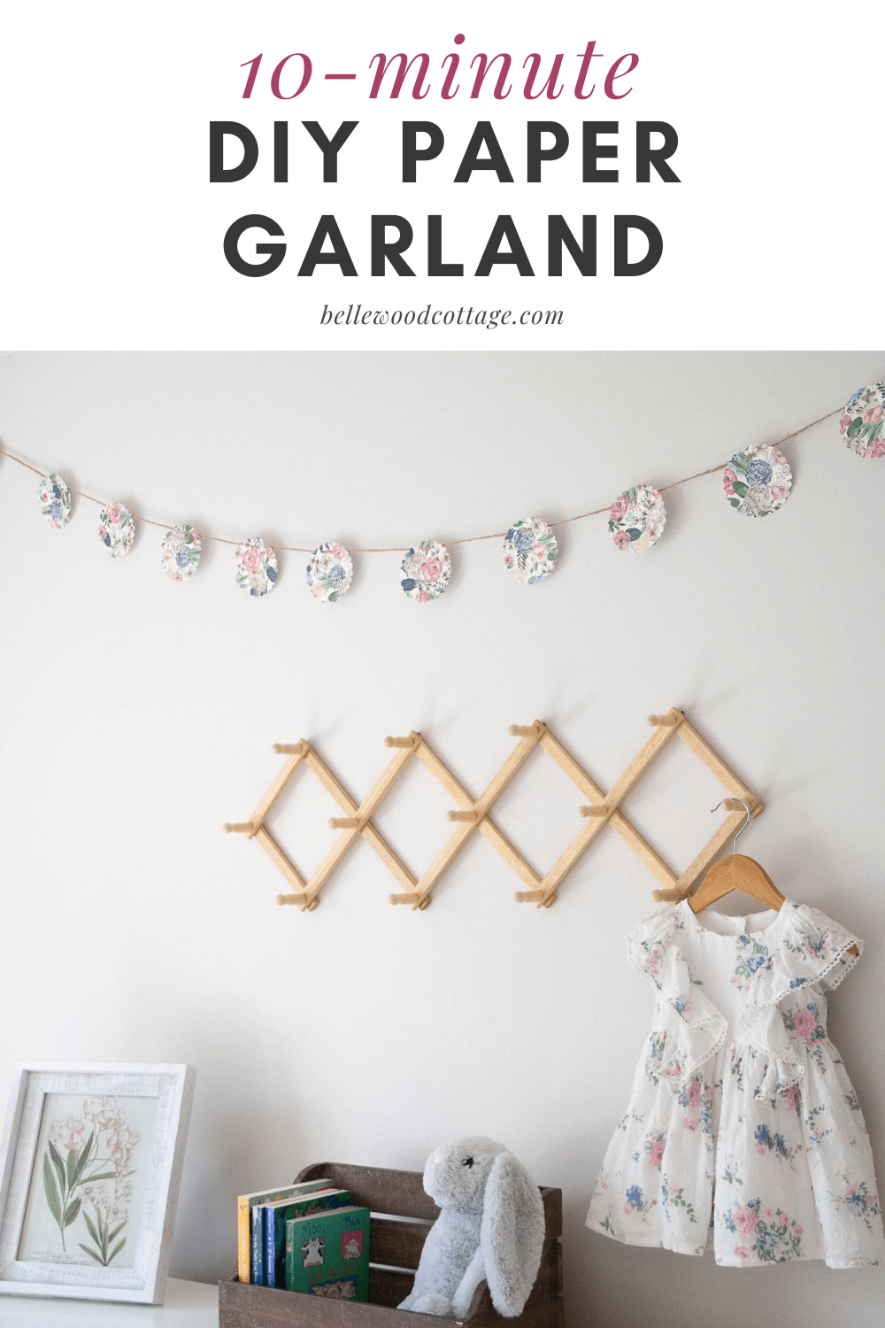 A diy paper garland hanging on the wall above other home decor like books and a peg rack.