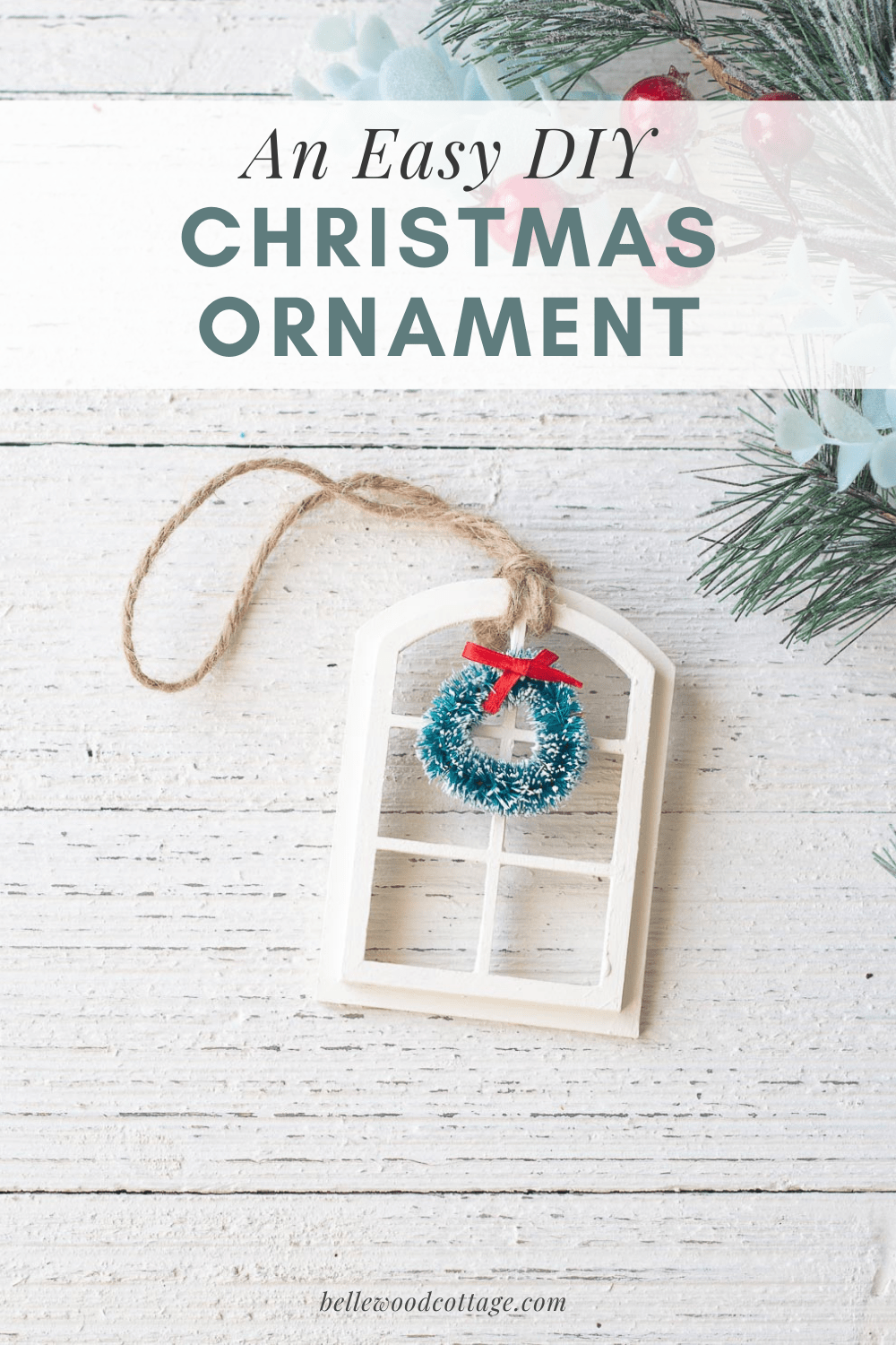 A DIY Christmas ornament (a miniature window with a wreath) on a wooden surface. 