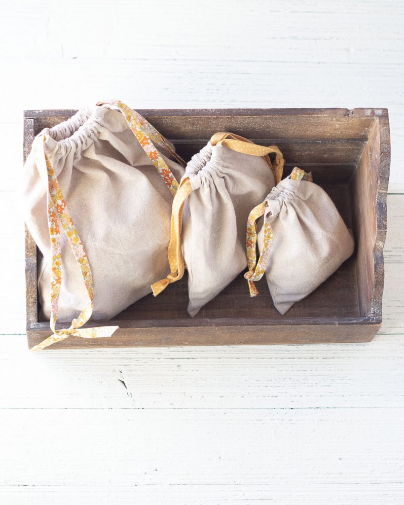 Three drawstring bags arranged in a wooden box.