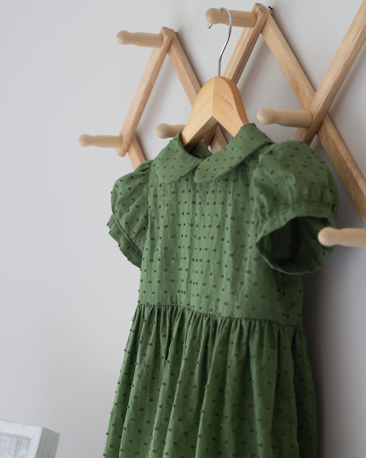 A toddler dress hanging on a wooden hanger.