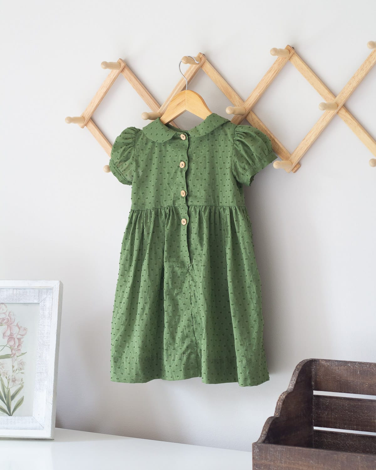 The back of a green toddler dress with wooden buttons.