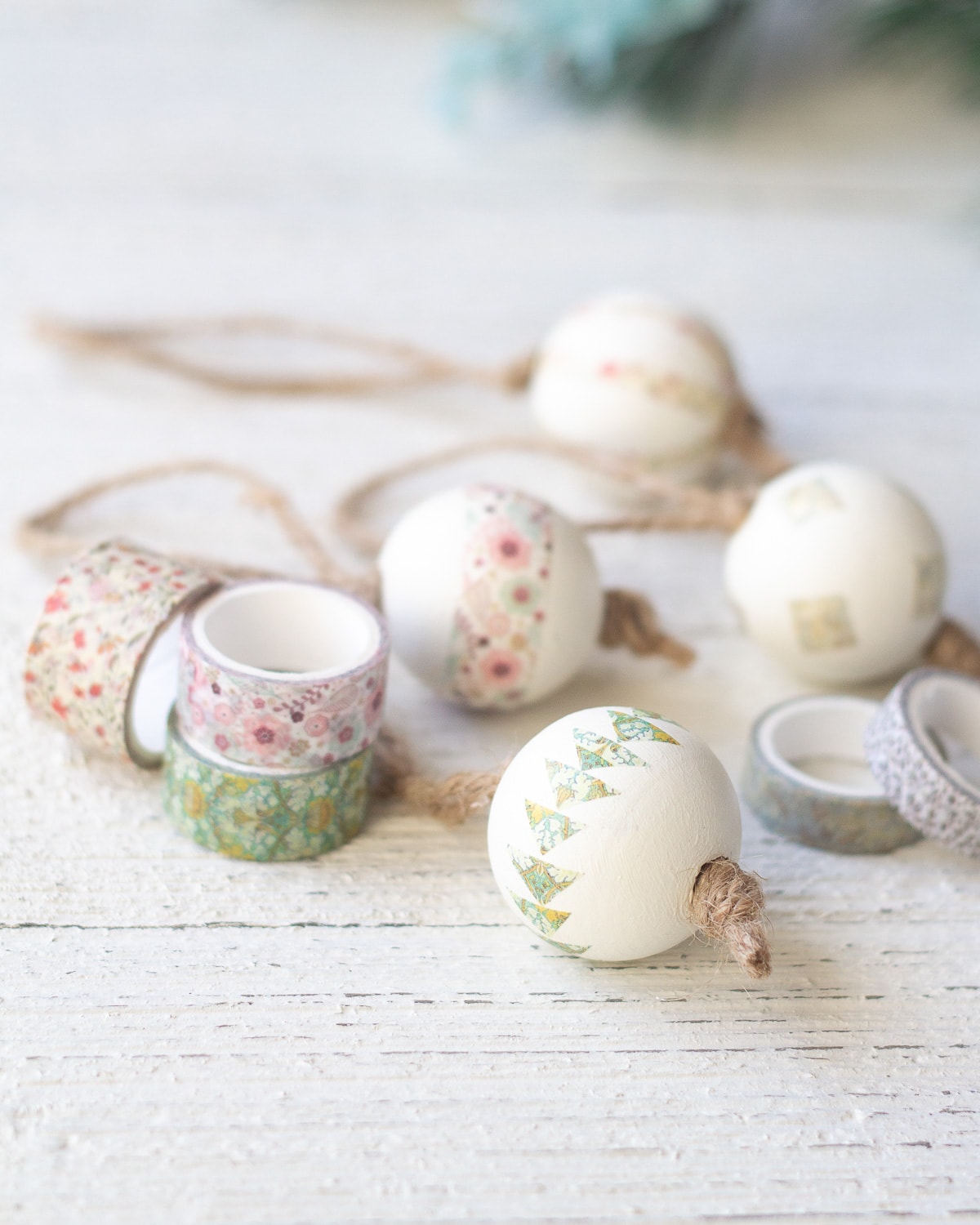 Spools of washi tape and decorated Christmas ornaments on a wooden surface.