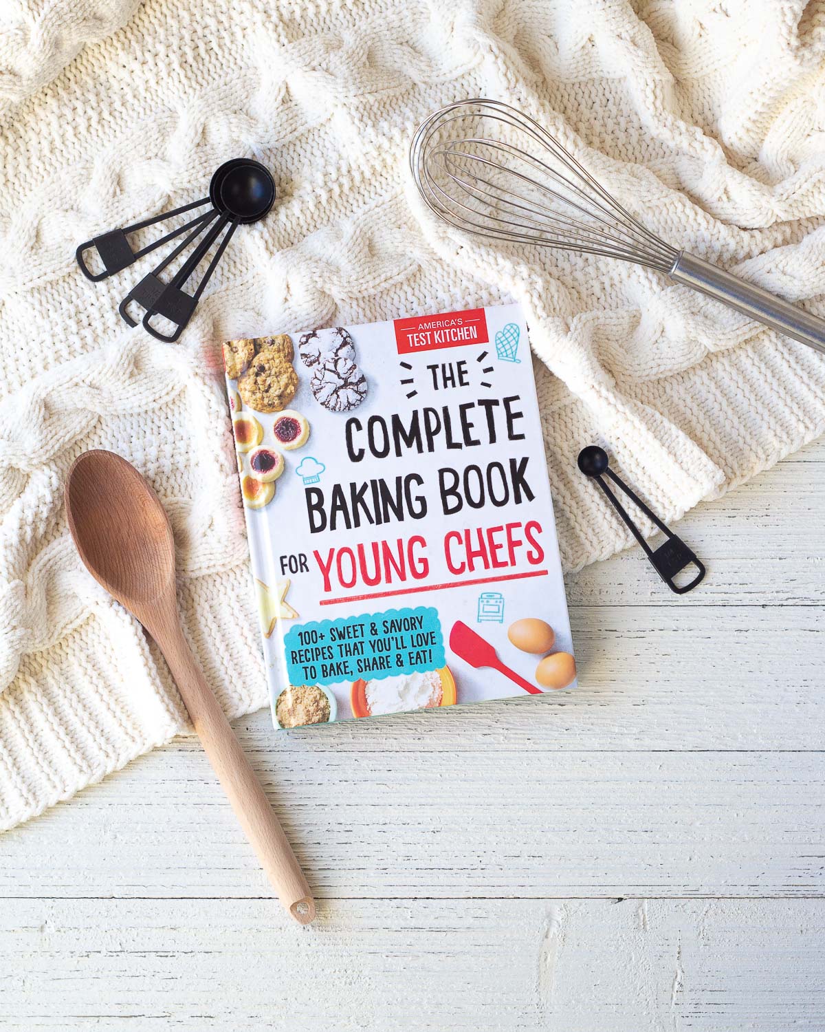 The Complete Baking Book for Young Chefs (a cookbook) on a wooden surface.