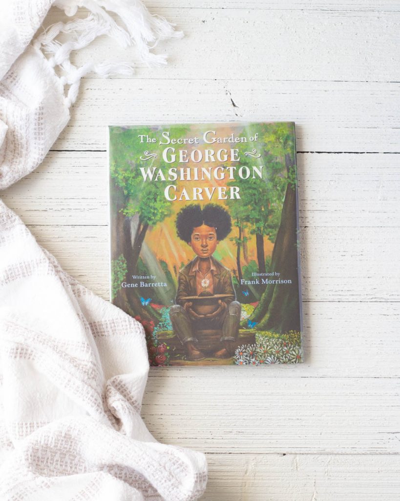 The Secret Life of George Washington Carver, a children's picture book from 2020, on a wooden surface.
