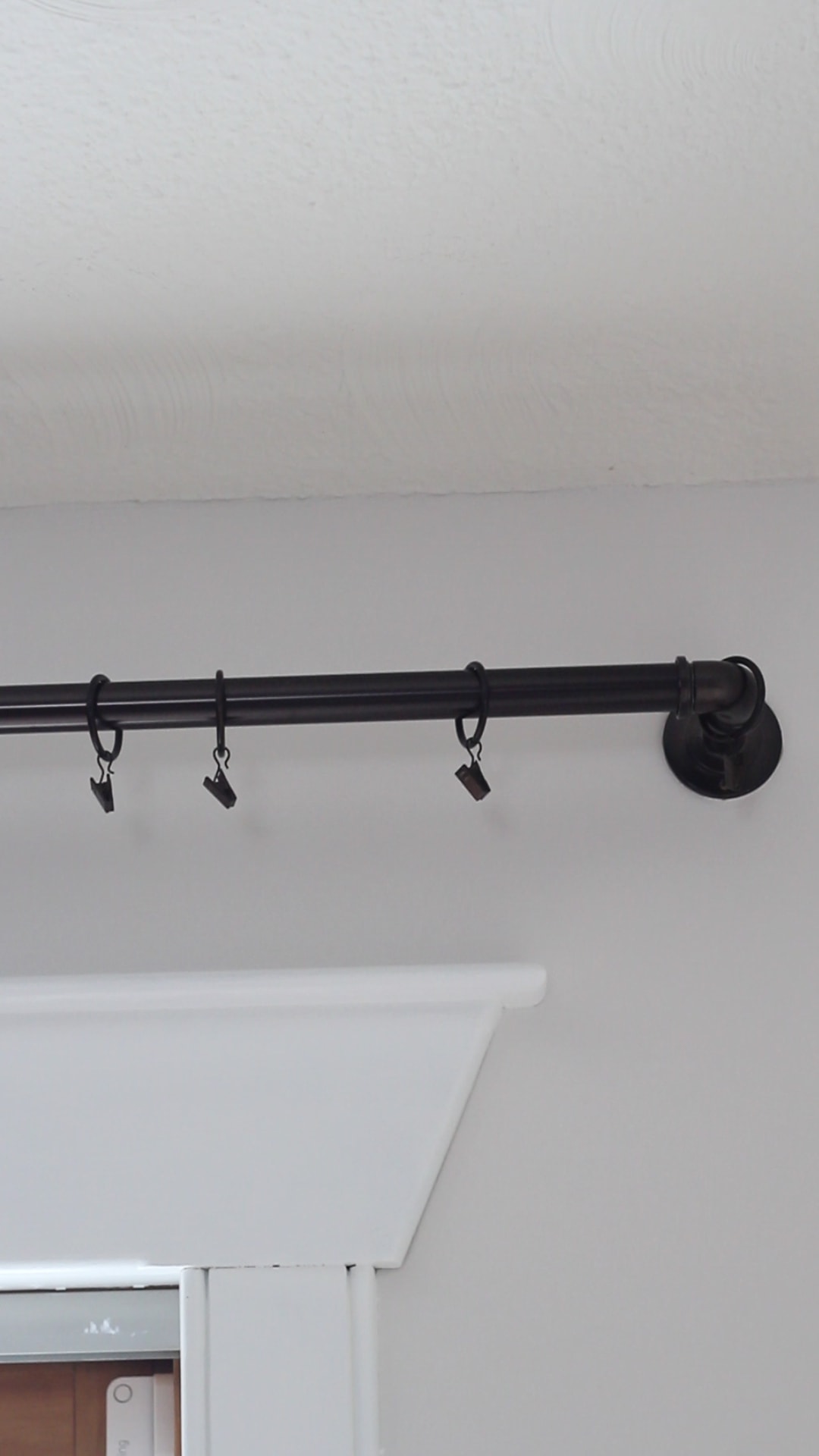 Curtain clips on a black curtain rod.