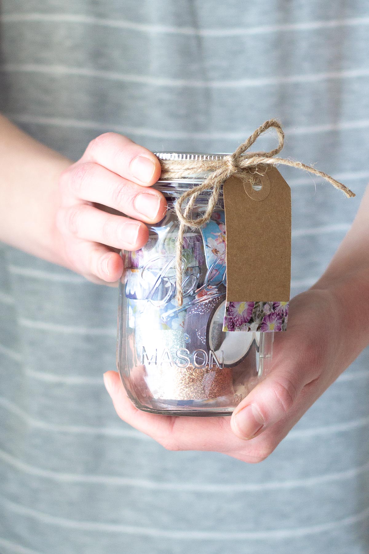 Holding a Washi Tape Mason Jar Gift Idea filled with colorful washi tape.