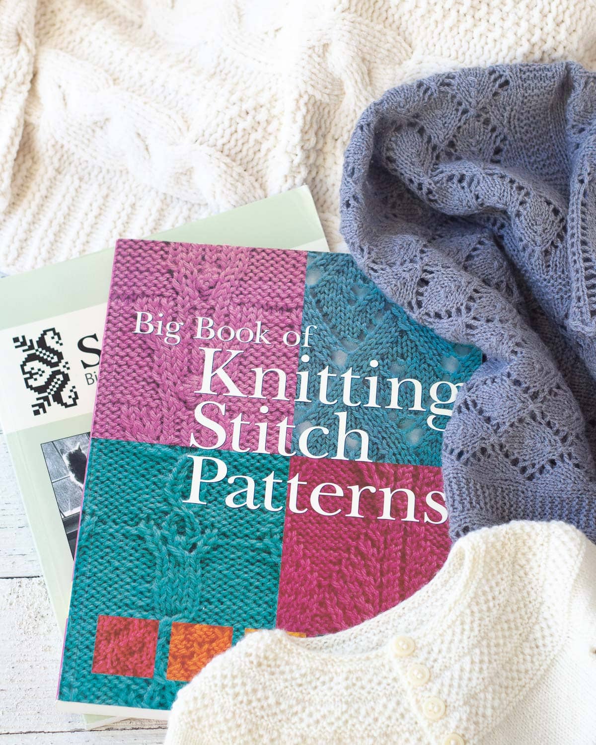 Knitting books surrounded by handknit items.