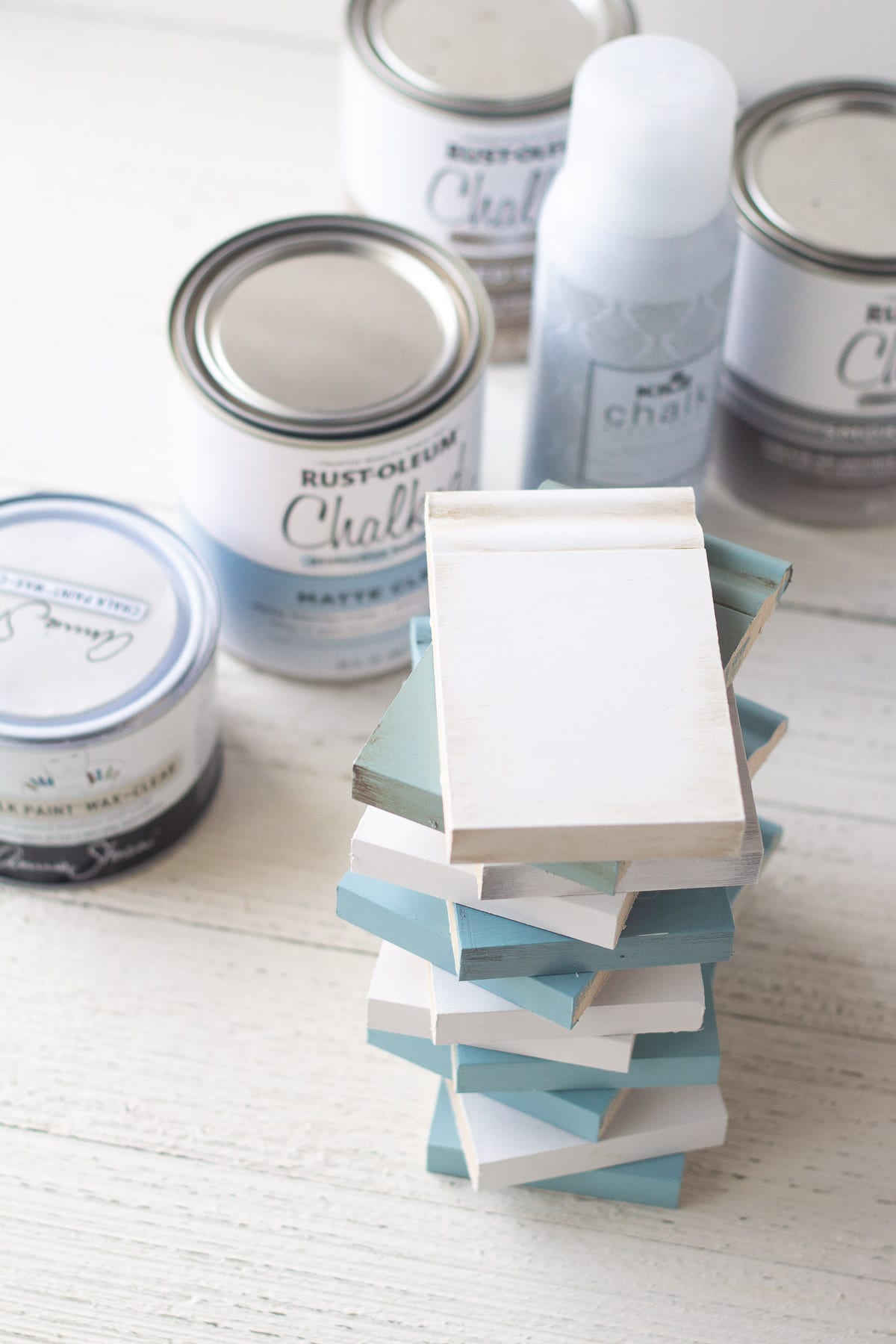 A stack of trim pieces painted with chalk paint and sealed with different top coats.