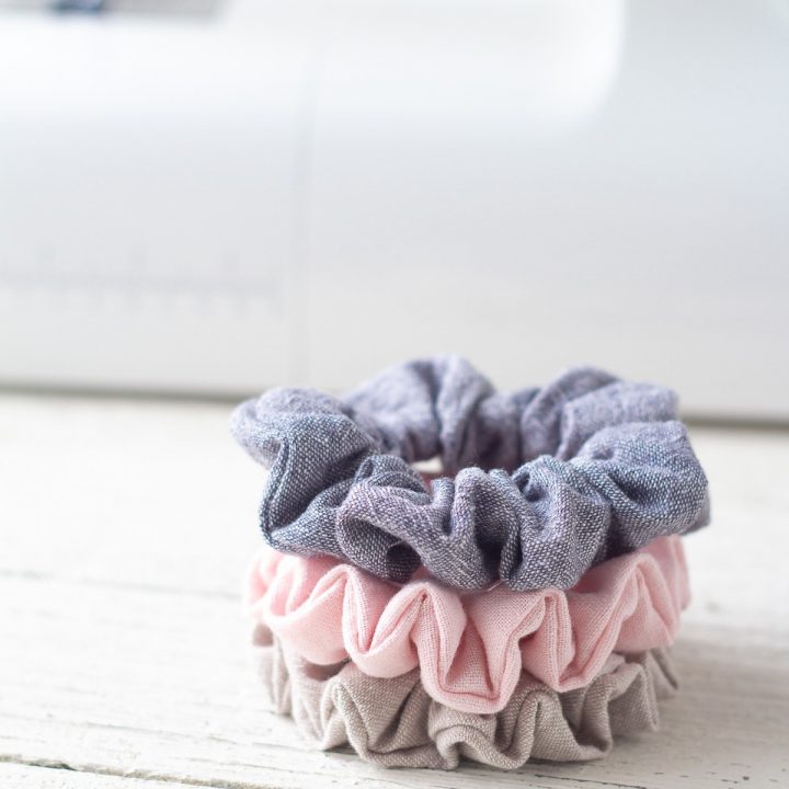 Handmade scrunchies in a stack on a wooden surface.