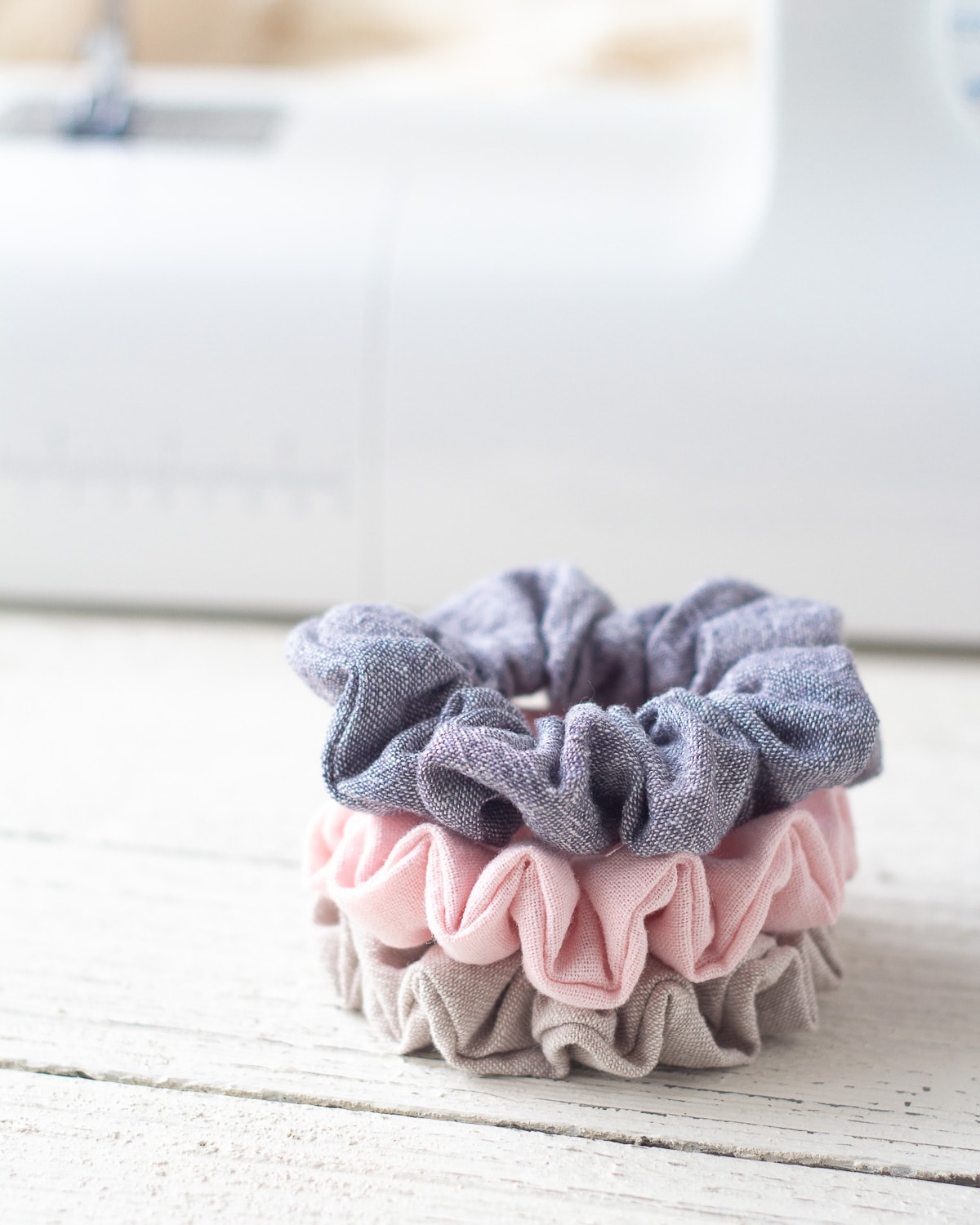 Handmade scrunchies in a stack on a wooden surface.