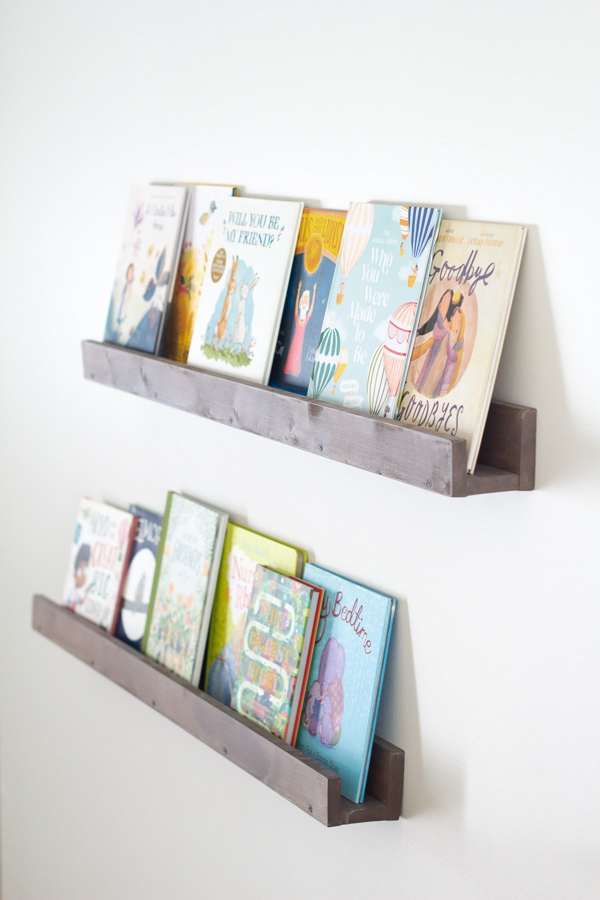 Kids' books displayed on wooden floating wall shelves.