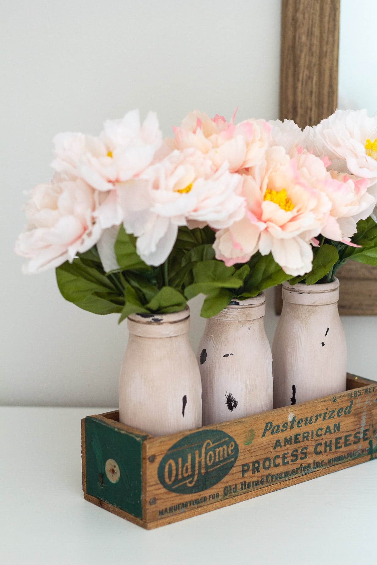Chalk painted and distressed milk bottles in a vintage cheese box.