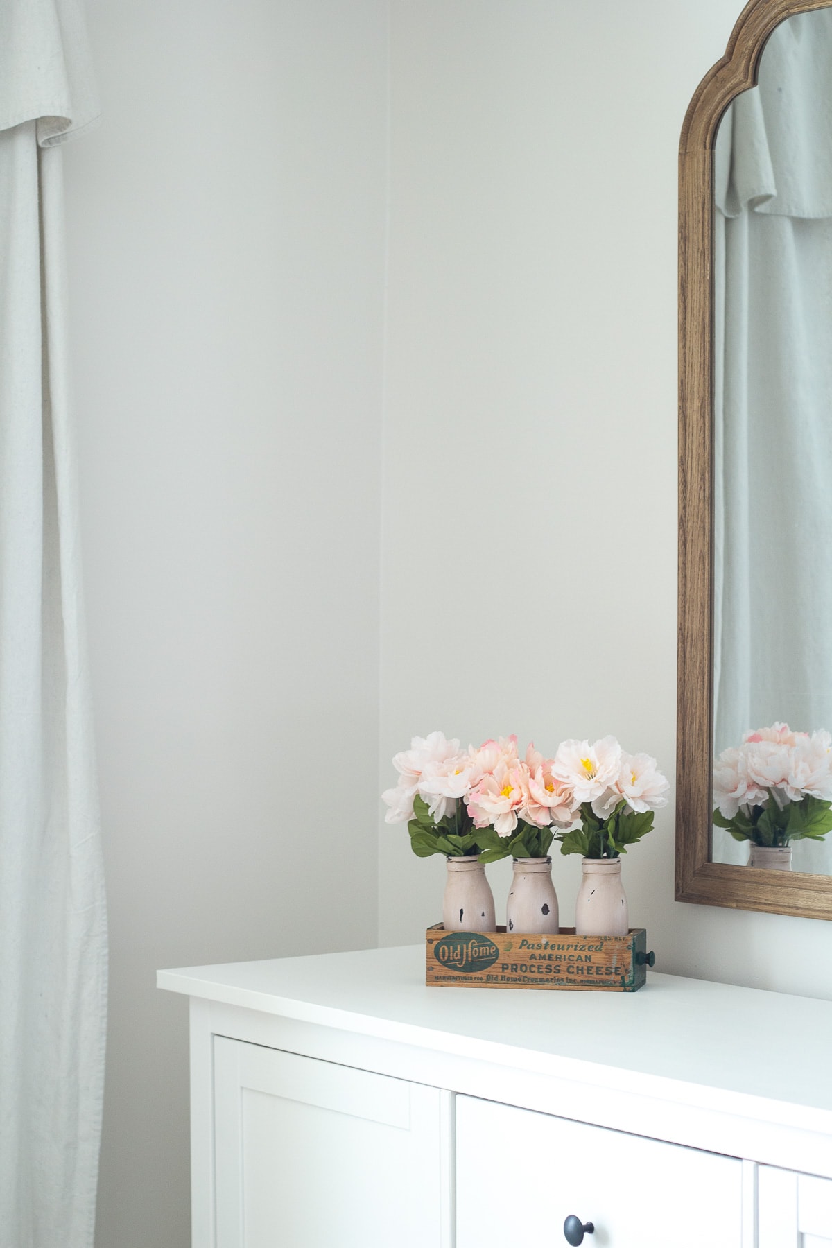 Vintage milk bottle décor idea for spring on a white sideboard.