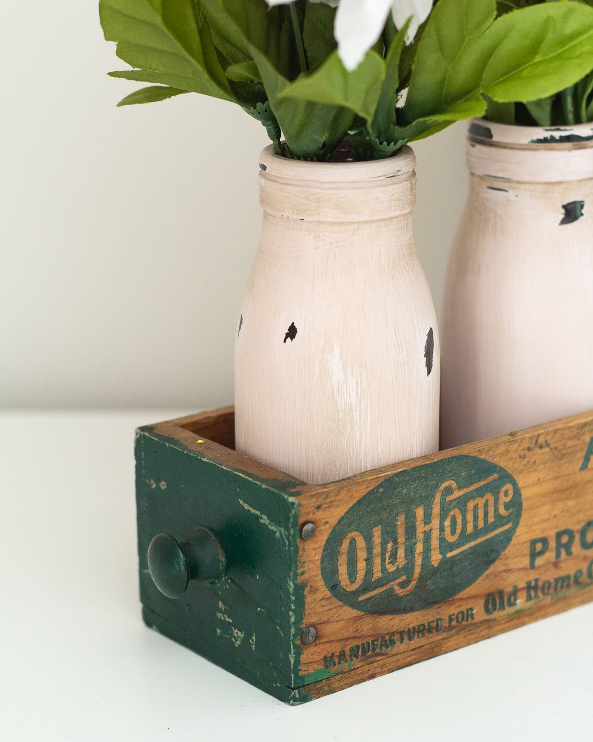 Chalk painted and distressed milk bottles in a vintage cheese box.