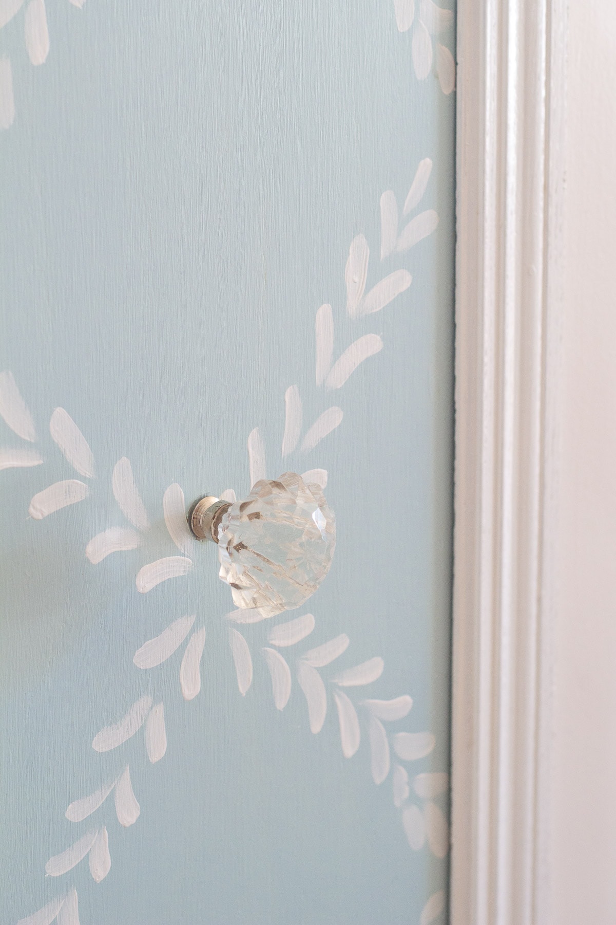 A glass doorknob installed on a chalk-painted pantry door.