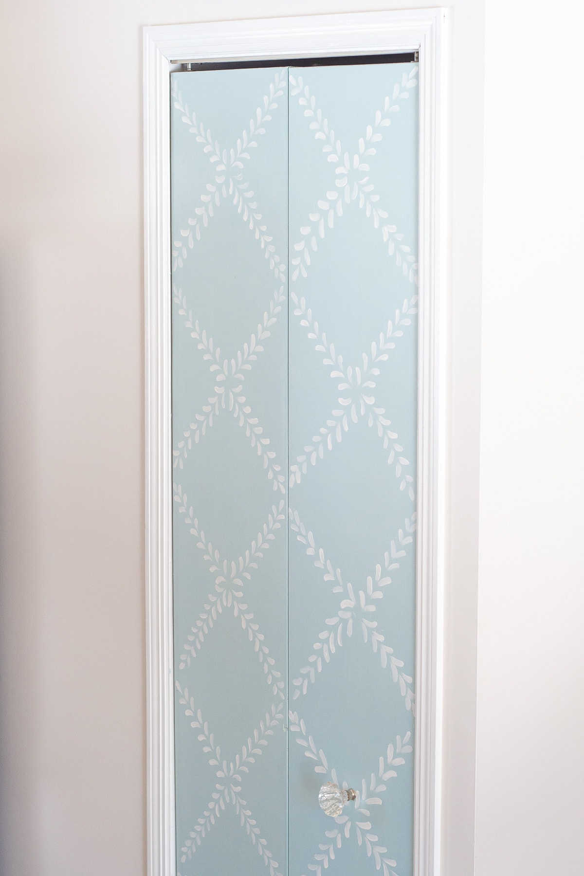 A pantry door painted with blue chalk paint and a white floral design.