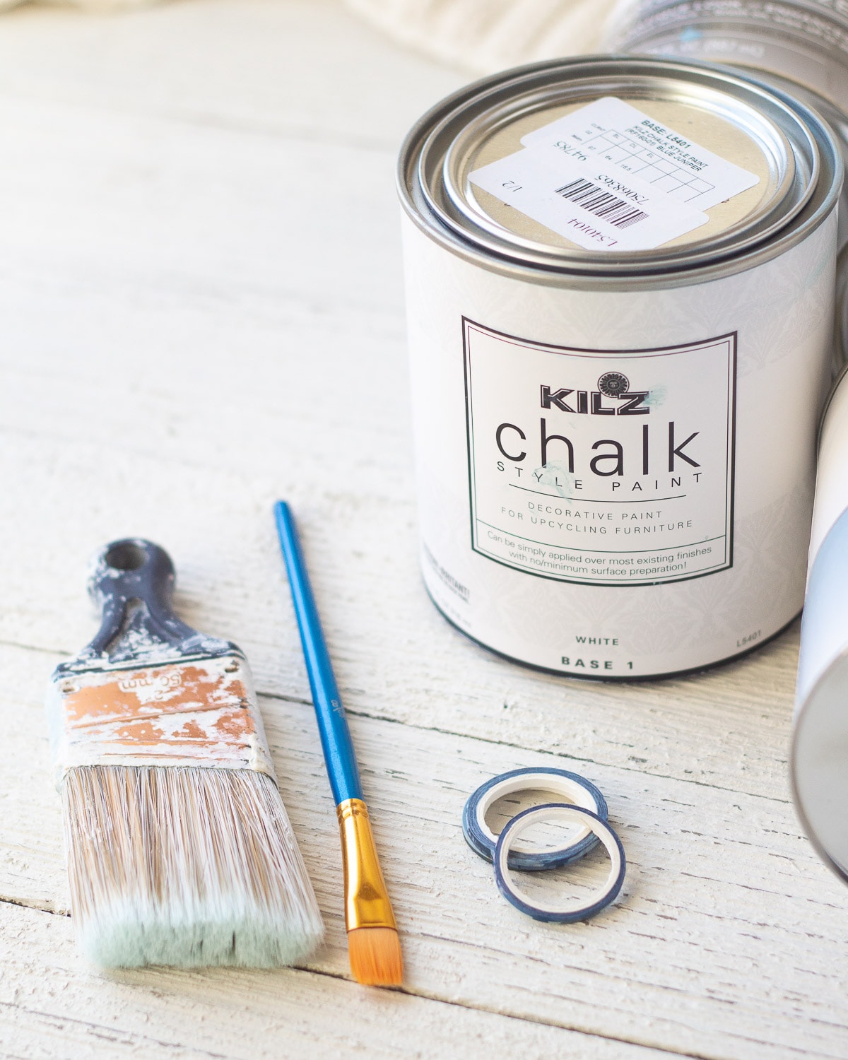 Paint brushes, washi tape, and a can of chalk style paint.