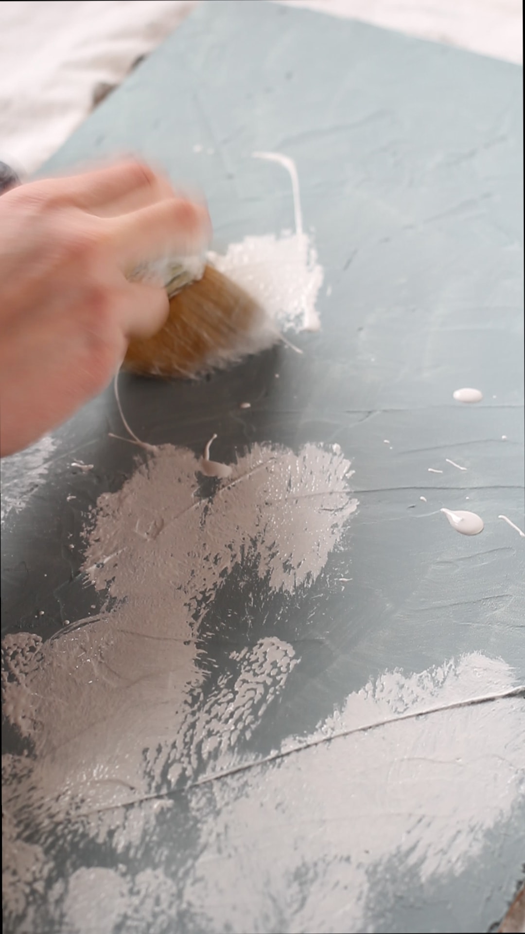 Applying white chalk painted to a plywood board painted blue.