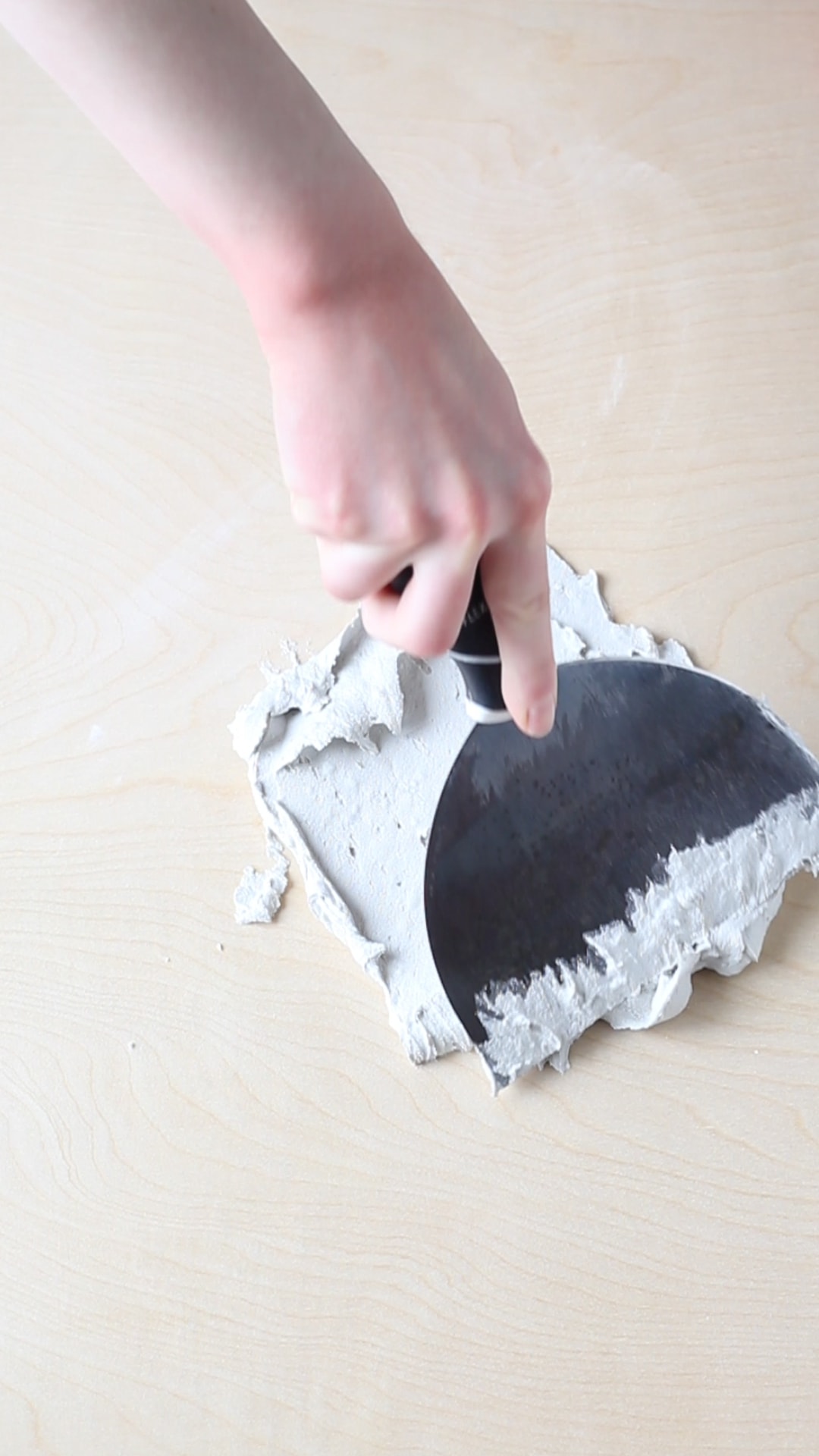 Spreading joint compound onto a plywood sheet to make a diy textured photography background.