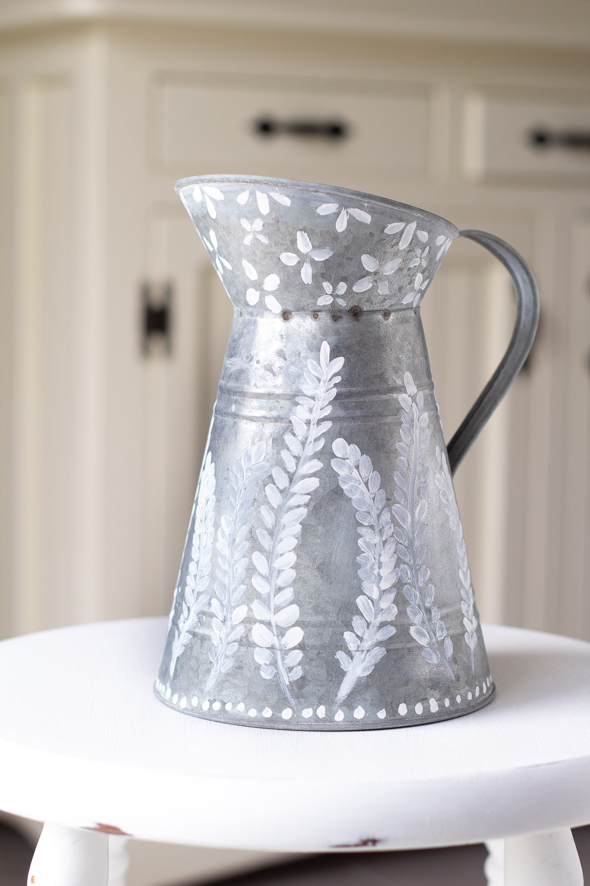 A galvanized pitcher with decorative painting.